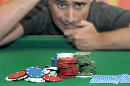 joueur de poker en face d'une table de jeu sur laquelle sont posés des cartes et des jetons de casino