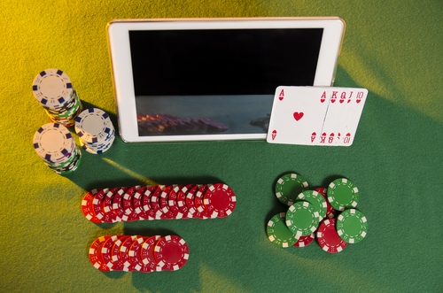 vue aérienne d'une tablette informatique posée sur une table de jeu avec des jetons de casino autour